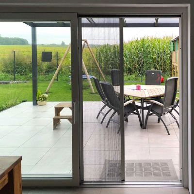 Fliegengitterplissee an Terrassentür. Teilweise geöffnet. Draußen ein Garten