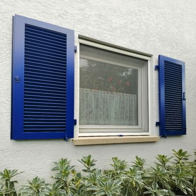 Fliegengitterrollo an Fenster mit blauen Fensterabdeckungen an der Seite