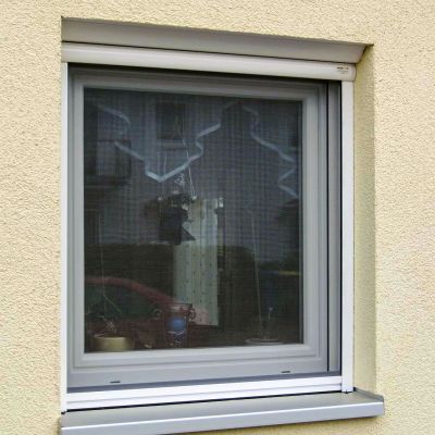 Fliegengitterrollo am Fenster, gelbe Hauswand