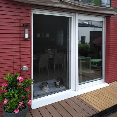Fliegengitterrollotür weiß an Terrasse. Rote Hauswände